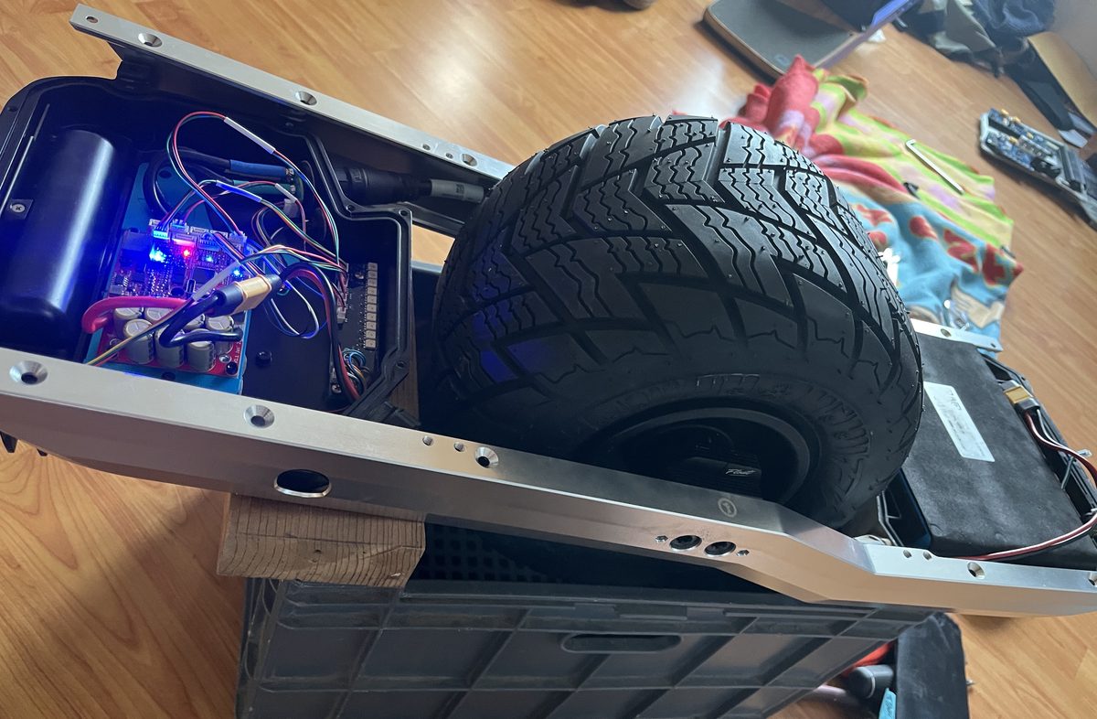 Open Onewheel GT showing VESC controller board, Pioneer tire, and custom battery — mid-build on the workbench